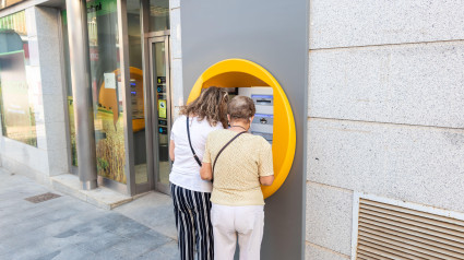 Dos mujeres jubiladas sacando dinero de un cajero automático