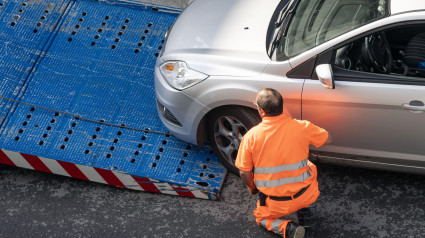 Trabajadora de asistencia en carretera levantando un coche en una grúa