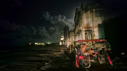 Dos hombres se sientan en un taxi-bicicleta durante un apagón en La Habana, tras la avería de una importante central eléctrica