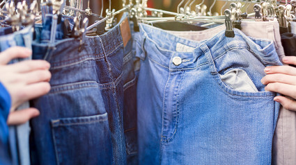 Primer plano de manos, buscando pantalones, jeans en un mercado de pulgas