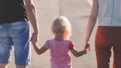 Una niña pasea de la mano de sus padres