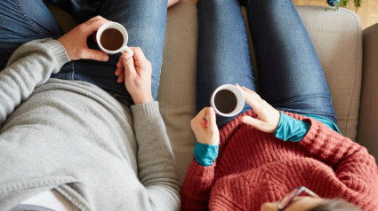 Vista aérea de una pareja sentada en un sofá sosteniendo una taza de café