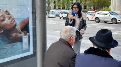 Pilar Cisneros habla con pasajeros en una de las marquesinas de la Puerta de Alcalá