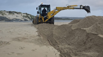 Una maquina de obras públicas actuando en el arenal para abrir el canal