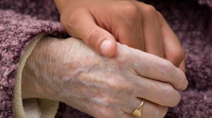 Primer plano de la mano de una mujer joven que sostiene la mano de una anciana