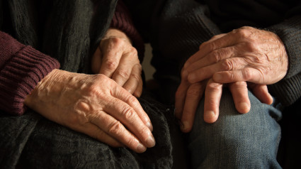 Manos de una anciana y un anciano sentados juntos