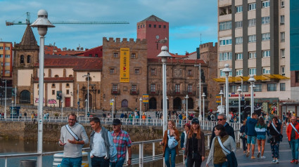 Gente paseando por los Jardines de la Reina, con Cimadevilla al fondo, en Gijón