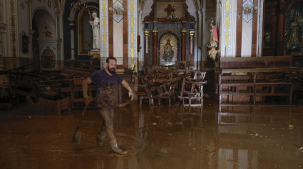 Un vecino de Paiporta limpia en el interior de la iglesia anegada por la DANA