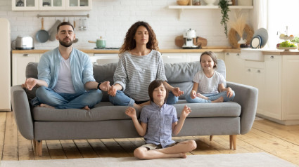 Familia joven relajada con niños lindos sentados y meditando