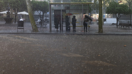 Varias personas esperan en la parada del bus durante la tormenta, a 30 de octubre de 2024, en Barcelona, Catalunya