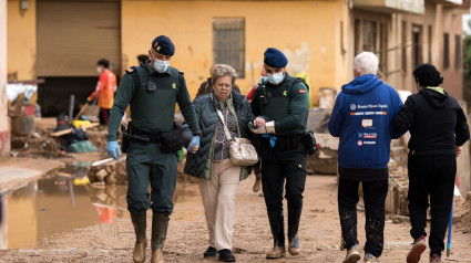 Dos agentes de la Guardia Civil ayudan a desplazarse a una mujer, a 4 de noviembre de 2024, en Paiporta, Valencia, Comunidad Valenciana