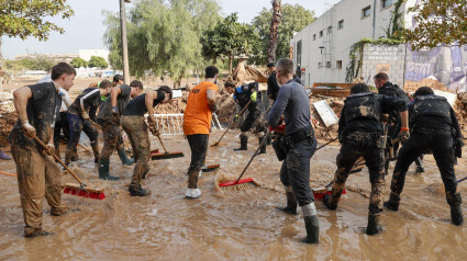 Voluntarios y fuerzas de seguridad trabajan para despejar una calle de Paiporta