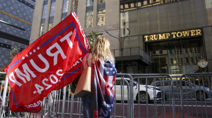 Una persona con una bandera de Donald Trump se encuentra frente a la Torre Trump en Nueva York, Nueva York, EE. UU., el 6 de noviembre de 2024