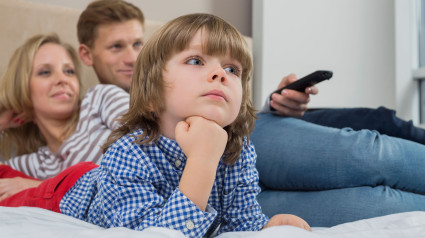 Familia viendo la televisión en el dormitorio