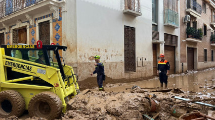 Miembros del equipo de Emergencias en Lorca retiran barro en una calle en Paiporta