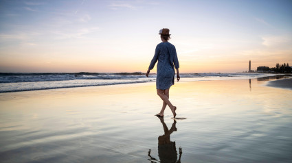 Mujer en un paseo nocturno, faro de Maspalomas al atardecer, Gran Canaria, España