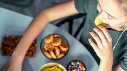 Una chica trabaja en una computadora y come comida rápida