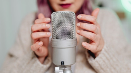 Una mujer tocando un micrófono para activar la Respuesta Meridiana Sensorial Autónoma (ASMR)