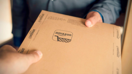 Un mensajero entrega un paquete de Amazon a un cliente. Amazon es una importante empresa mundial de compras en línea