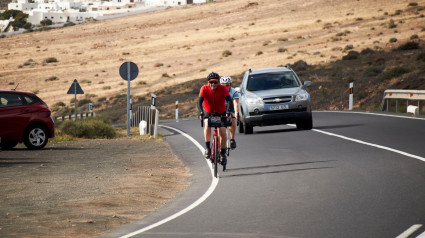 Dos ciclistas subiendo una colina en una carretera de montaña en Lanzarote, Islas Canarias, España