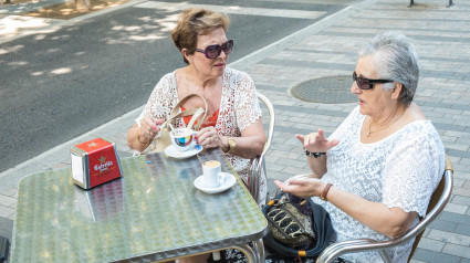 Una pareja de ancianos tomando un café en una mesa al aire libre en la calle, cafetería al aire libre, suburbio de la ciudad de Terrassa, Barcelona, ​​Cataluña