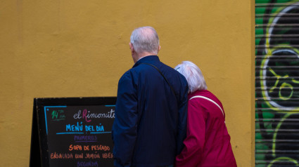 Una pareja mayor lee el menú de un restaurante mientras se toman de la mano