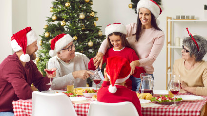 Feliz y sonriente madre e hija cortando pavo en el almuerzo familiar de Navidad en casa