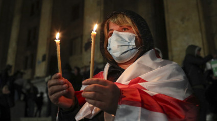 Un partidario de la oposición georgiana sostiene velas encendidas durante una manifestación frente al edificio del Parlamento en Tbilisi, Georgia.