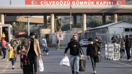 Los sirios caminan con sus pertenencias en el lado turco de la frontera de Cilvegozu, entre Turquía y Siria, en el distrito de Reyhanli de Hatay