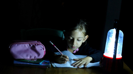 Niña haciendo los deberes con una linterna