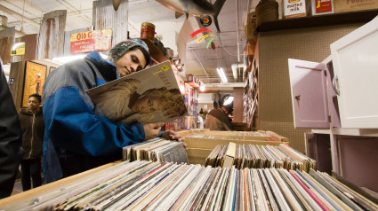 Un hombre mira un disco de vinilo en venta en una tienda de antigüedades.