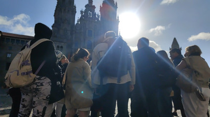 Un grupo de turistas atiende a las explicaciones de la guía en el Obradoiro