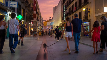 Familia paseando con un perro pequeño cerca de la Puerta del Sol, Madrid, España, resplandor del atardecer