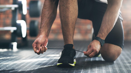 Preparándose para salir. Un deportista irreconocible atándose los cordones de los zapatos en un gimnasio.