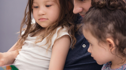 Un padre le lee un cuento a sus hijas