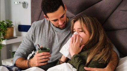 Marido cuida a su esposa porque tiene gripe en la cama