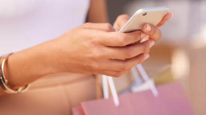 Manos con smartphone, mujer y bolsa de compras en un centro comercial para terapia de compras con tecnología y comunicación. Aplicación móvil, zoom de teléfono y compras