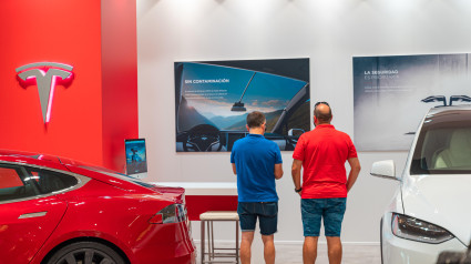 Dos compradores de un coche eléctrico Tesla Model S expuesto en una tienda Tesla de Valencia