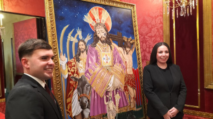 El presentador y la autora del cartel de la Semana Santa posan junto a la obra gráfica