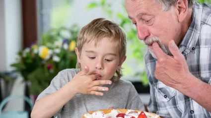 Un abuelo y su nieto comiéndose una tarta