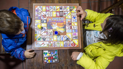 Hermanos pequeños jugando al Juego de la Oca sobre una mesa de madera antigua. Vista aérea. Juego de mesa tradicional