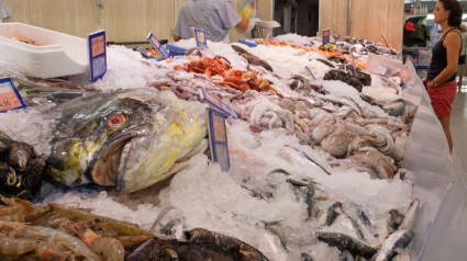 Selección de pescado fresco en exposición en un supermercado español, con un gran mahi-mahi, dorado o pez dorado en primer plano, España