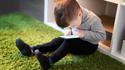 Niño pequeño jugando a juegos en un teléfono móvil