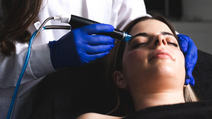 Una mujer joven limpiándose la cara en una clínica estética.