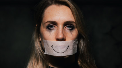 2T8W7GA abuse and domestic violence. sad depressed woman hide her mouth behind fake drawn smile on paper tape. depression and mental health