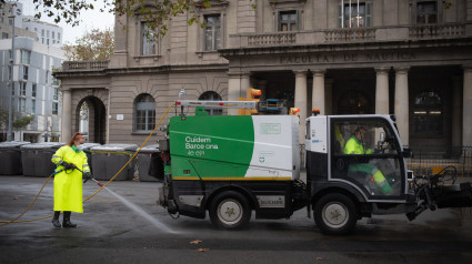 (Una trabajadora de la limpieza riega una calle en Barcelona