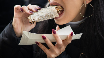 Mujer con uñas bonitas comiendo comida vorazmente