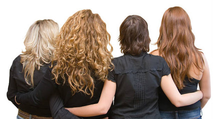 Four girls, four hair colours - blond, chestnut, brunette, redhead. All with black blouses or tops, linking arms. Isolated