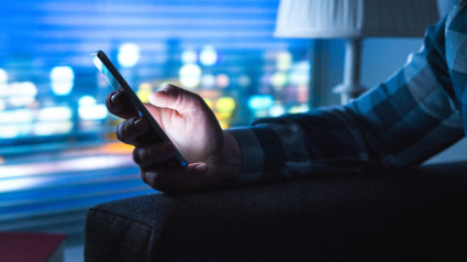 Hombre usando un teléfono inteligente en casa por la noche