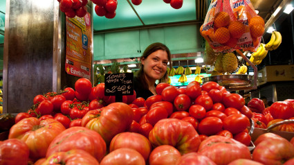 Vendedor sonriendo detrás de los tomates, el mercado de la Boquería, La Rambla, Barcelona